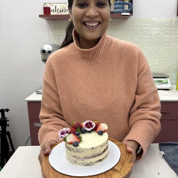 Baker presenting a naked berry cake at Crème It Up studio Chandigarh